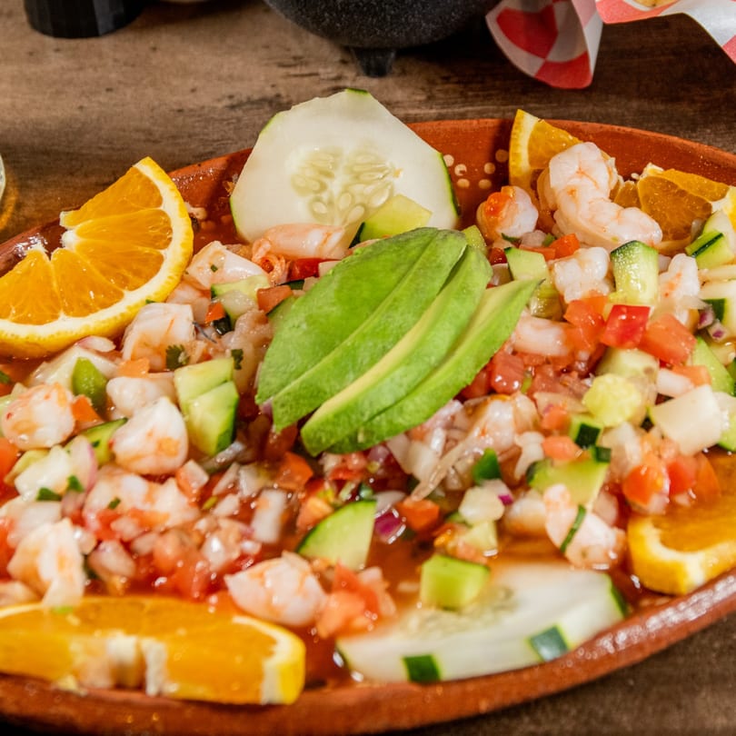 Reyes Mexican Grill's shrimp ceviche with avocado, cucumber, and orange slices in a rustic bowl.