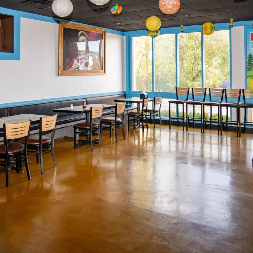 Interior of Reyes Mexican Grill with tables, chairs, and large windows, decorated with colorful lanterns.