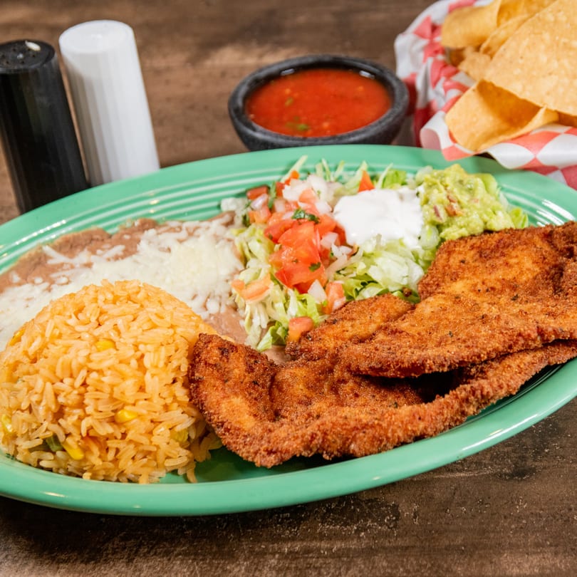 Reyes Mexican Grill's breaded chicken, rice, refried beans, salad, guacamole, and sour cream.