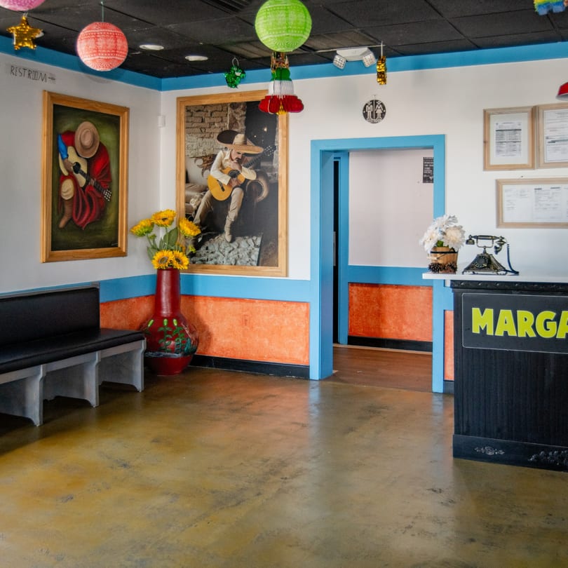 Reyes Mexican Grill's vibrant waiting area with Mexican art, colorful decor, and a host stand.
